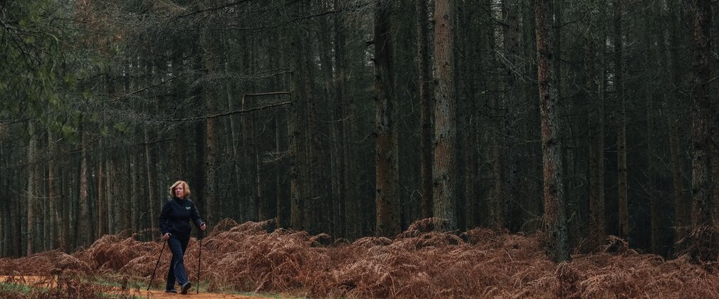 A woman enjoys nordic walking through the trees