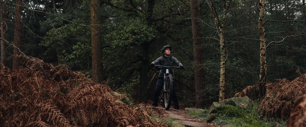 Women pauses to look around the forest on her bike