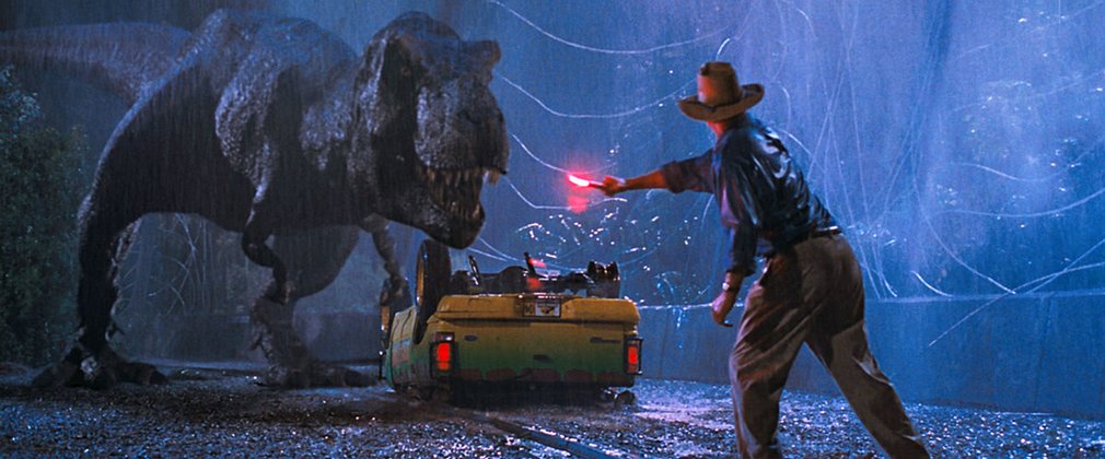 Dr Alan Grant, played by Sam Neill, waves a flare to distract an approach tyrannosaurus rex. 