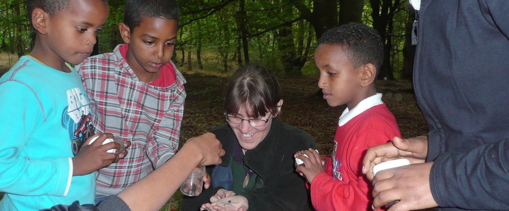 Forest leader showing school children small animals in the forest classroom 