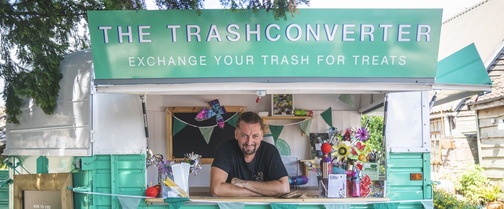 The trashconverter - a bright turquoise van with a friendly man in the hatch waiting to take your trash