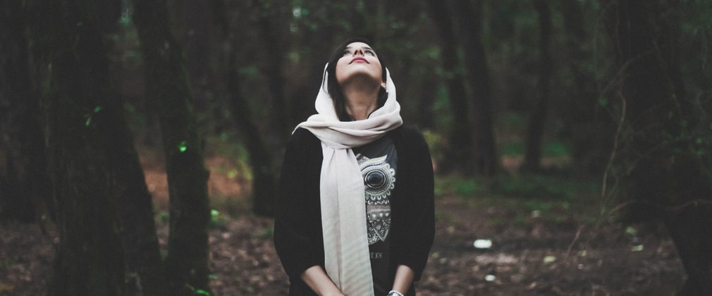 Woman looking up into forest canopy