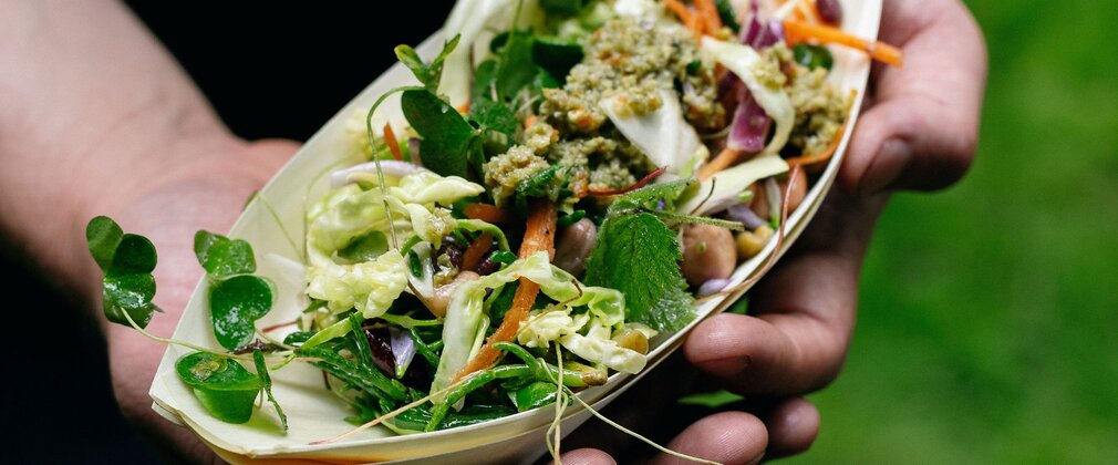 A bowl of salad being held towards the camera