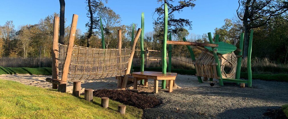 A children's play area consisting of a rope bridge and a raised play area