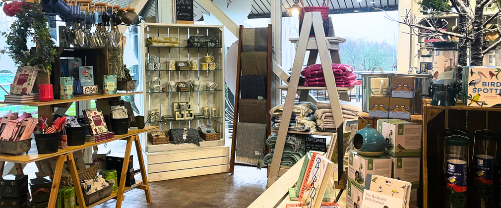 Inside of a shop with shelves of blankets and books to sell. 