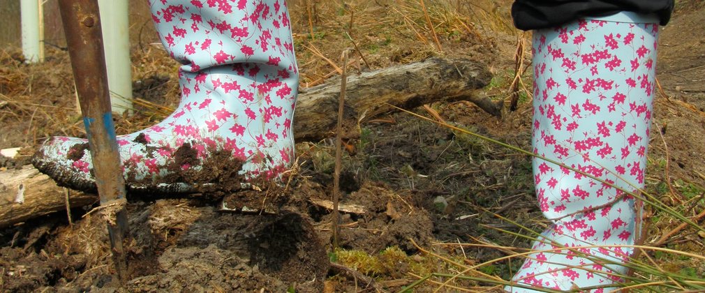 Close up of wellies planting a tree in the forest 