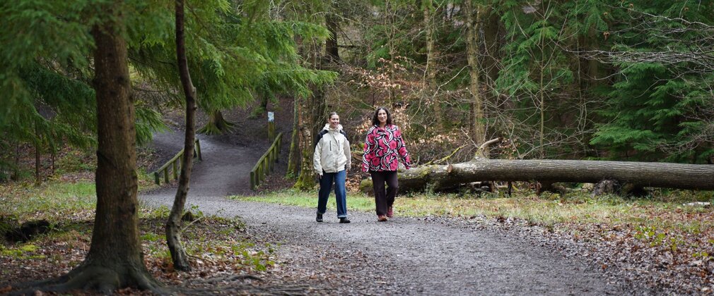 Two women walking along a forest path.