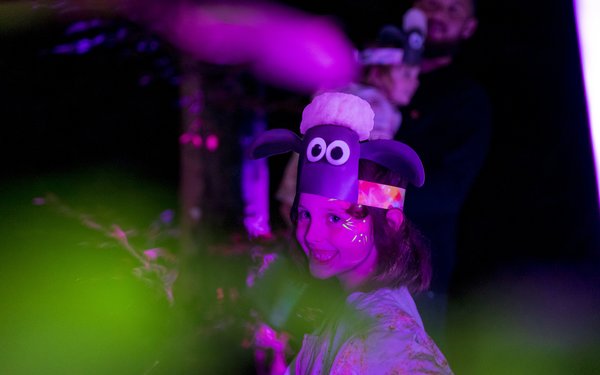 Girl in shaun the sheep head band wearing UV paint in the forest