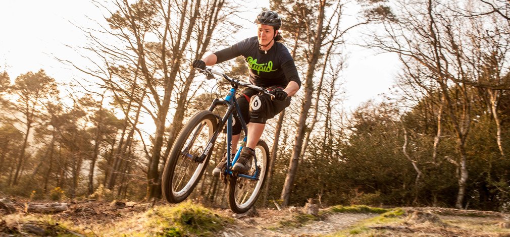 Lady jumping off a jump on a mountain bike track