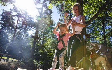 Woman and child in harnesses on adventure climbing trail