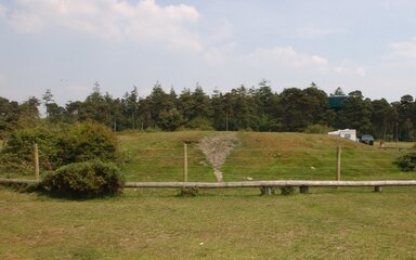 A large grassy mound surrounded by a fence.