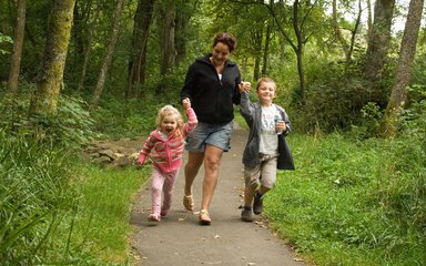 Young family walking through the green forest 