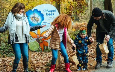 Family in front of a Superworm panel pretending to be a bee