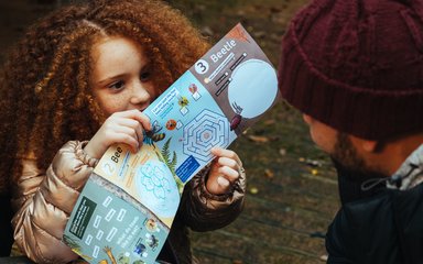 Young girl pointing out an image in a Superworm activity sheet
