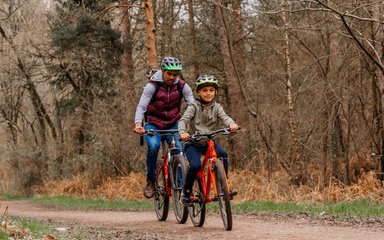 A father and son riding their bikes through the forest