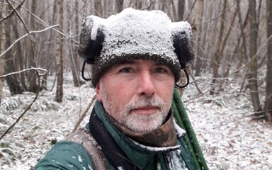 A man taking a selfie in a snow covered forest.