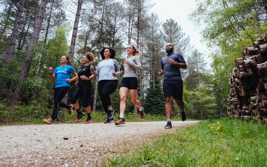 Five people running through forest