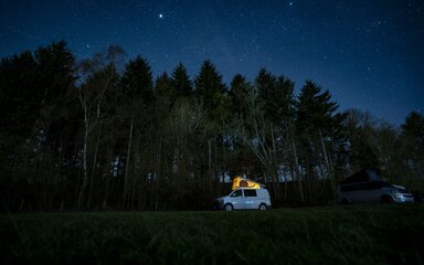 Campervan against the forest and night sky