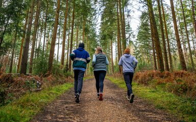 Three people running in a forest