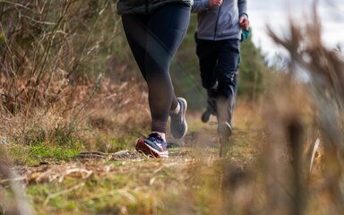 Two runners close up of legs running through a forest path