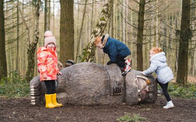 three children in a forest with a Gruffalo scuplture