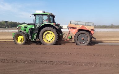 Tractor spreading seed in field to plant trees