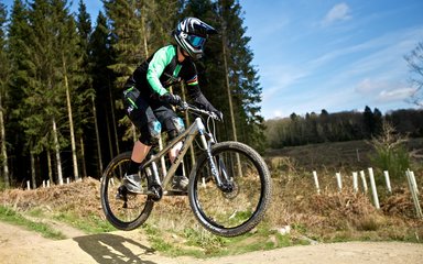 mountain biker jumping on a single track trail through the woods 