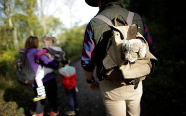 A family with backpacks walking down a forest track