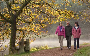 walkers enjoying a walk around a woodland lake in autumn 