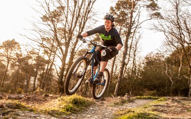 Lady jumping off a jump on a mountain bike track