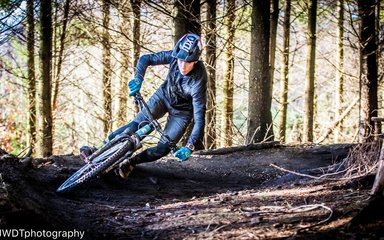 Man on mountain bike going round tight corner on trail in the forest 