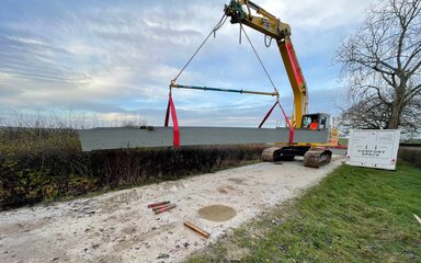 A yellow crane lifting a bridge section into place.