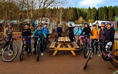 A group of smiling women on their mountain bikes posing for a photo.