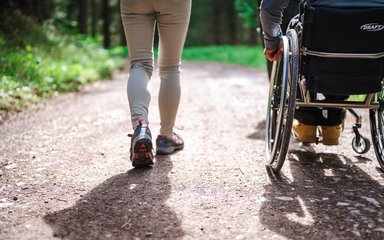 A women walking next to a man in a wheelchair on a forest track
