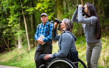 A couple bird spotting through binoculars with a guide in the background
