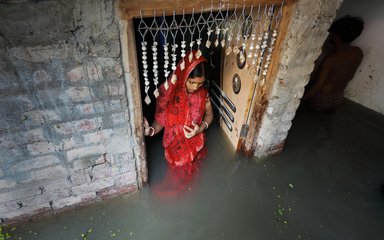 Indian woman in red wedding gown walking in flooded home