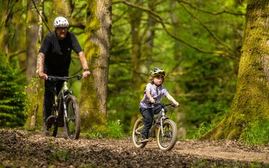 Man and child riding bikes in a forest 