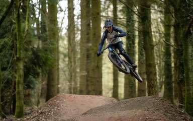 Cyclist jumping on a mountain bike trail in the Forest of Dean