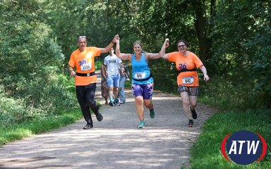 3 people holding hands in the air as they run through a forest