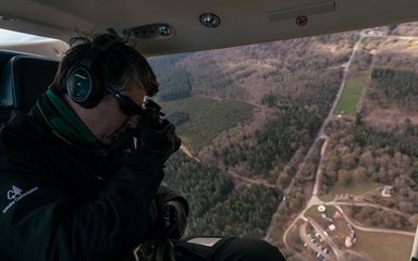 Man doing an aerial survey of the forest from a helicopter