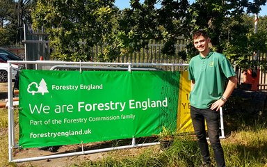 Forestry England volunteer stood next to sign