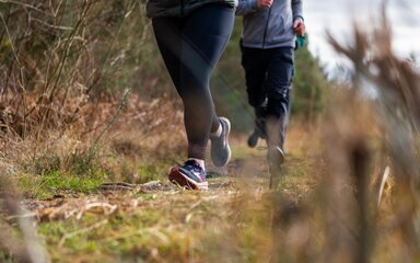 Close-up of two pairs of feet running long a grassy surface