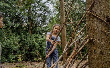 Child building a den out of sticks in the forest