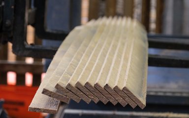 Long thin planks of oak wood that have just been cut to size sit concertinaed on a lifting fork 