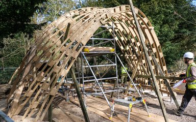 A wooden timber set of arches stand from the ground to form a semi circle shape of arches that people could walk under.