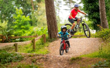 A woman and child on bikes, cycling in the forest.