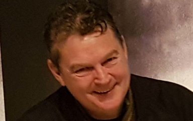 A man with dark hair smiles at the camera