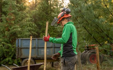 Woman holding wooden stake wearing forestry gear