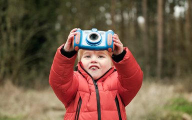 Young boy taking a photograph in the forest