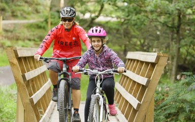 Woman and girl cycling over bridge